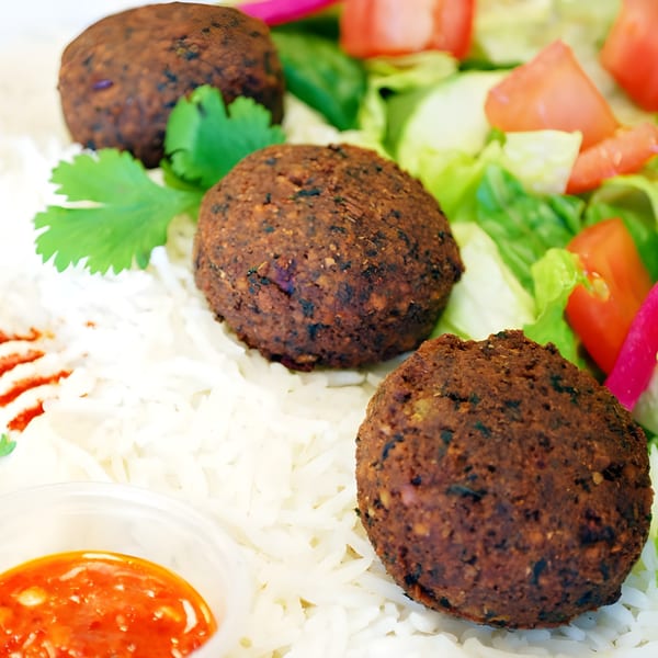 Al Hamra Kabob Grill's falafel plate with rice, fresh salad, and a side of red sauce.