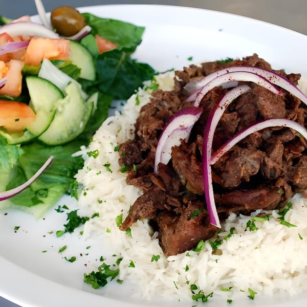 Al Hamra Kabob Grill's Mediterranean dish with rice, meat, red onions, and a side salad.